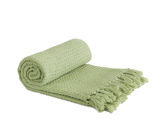 Rolled green throw blanket with tassels on a white background